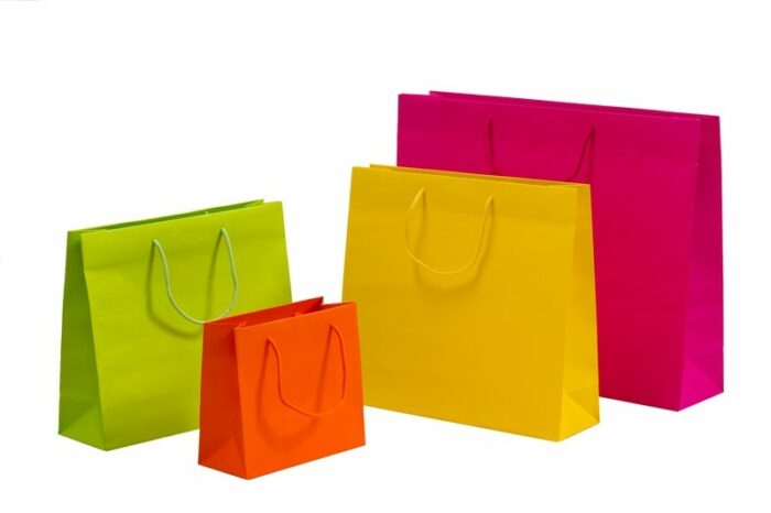 vier bunte Papiertaschen mit Baumwollkordel in Taschenfarbe, in verschiedenen Größen und Farben pink orange grün und gelb