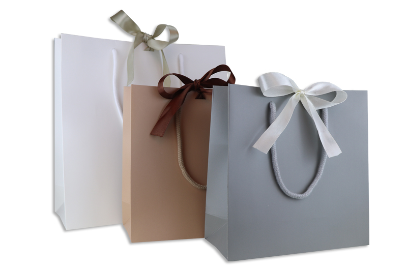 Geschenktasche Present bei tausendtypentragetaschen in weiß, grau und camel mit passender Baumwollkordel und Satinband zum verschließen der Tasche