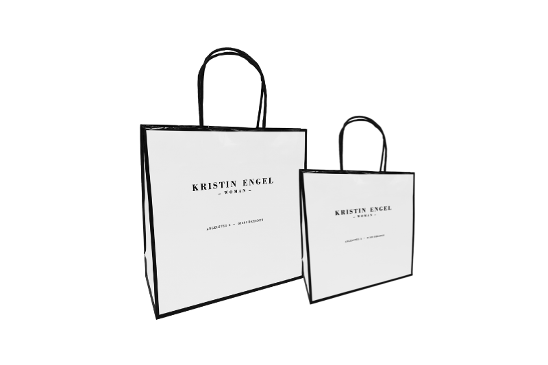 Kristin Engel Papiertasche weiß glänzend in zwei Größen, schwarze Papierkordel, schwarzer Rahmen und Firmendruck bei tausendtypentragetaschen